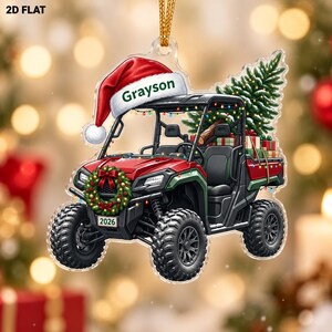May include: A flat acrylic ornament shaped like a red UTV with a Santa hat on the roof featuring the name Grayson. The vehicle has a Christmas wreath on the front with a 2026 license plate, a pine tree in the cargo bed, and colorful string lights.