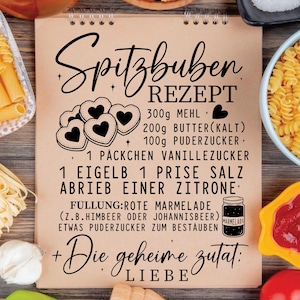 May include: A recipe for Spitzbuben cookies is displayed on a spiral-bound notepad. The recipe includes ingredients like flour, butter, and powdered sugar. The notepad features a heart-shaped cookie illustration and the words "Die geheime Zutat: LIEBE."