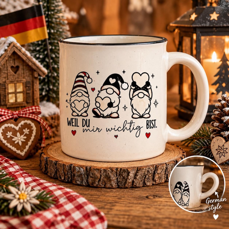 Puede incluir: Una taza de cer&aacute;mica color crema con borde negro, que presenta un gr&aacute;fico de tres gnomos sosteniendo corazones y el texto en alem&aacute;n "WEIL DU mir wichtig BIST." La taza se muestra sobre una rodaja de madera, con una peque&ntilde;a imagen insertada.