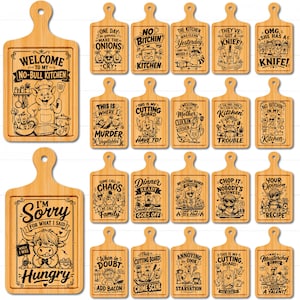 May include: A collection of rectangular bamboo cutting boards with rounded handles, each featuring unique laser-engraved illustrations and humorous kitchen-themed text such as Welcome to my No-Bull Kitchen, No Bitchin in my Kitchen, and I'm Sorry for What I Said.