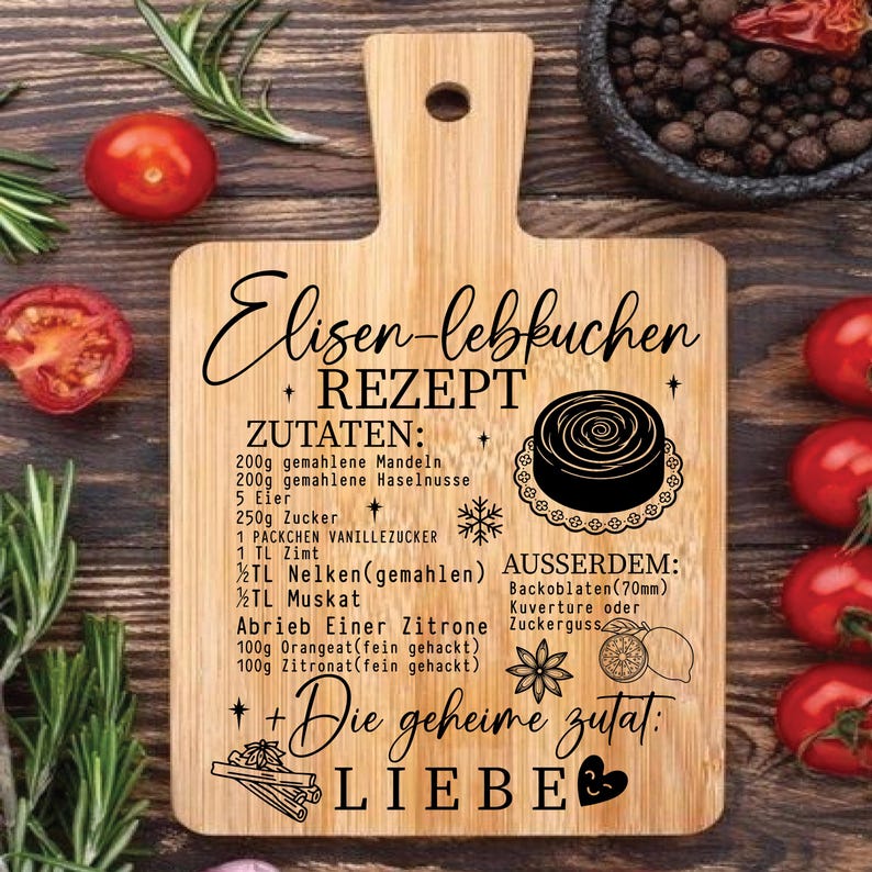 May include: A wooden cutting board with a handle, featuring a recipe for Elisen Lebkuchen. The recipe is written in German with ingredients listed. The board has a decorative design with a cake illustration and the word "LIEBE".