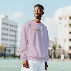 Könnte beinhalten: Helllila Sweatshirt mit dem Text "SOUNDS GAY I'M IN" in Regenbogenfarben. Das Sweatshirt hat einen Rundhalsausschnitt und ist aus einem weichen Material. Die Person trägt weiße Shorts.