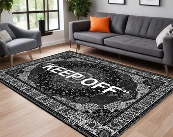 May include: Black and white patterned rug with the words "KEEP OFF" in large white letters. The rug has a detailed border and a central design with floral and paisley elements. The rug is in a living room setting.