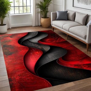 May include: A rectangular area rug with a modern abstract design. The rug features a bold color palette of red and black, with a flowing, wave-like pattern. The rug is placed on a hardwood floor, with a sofa and plants in the background.
