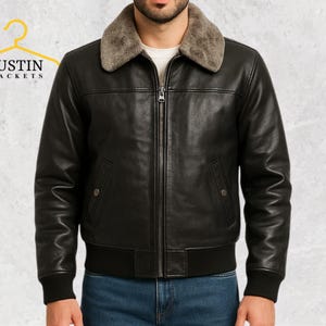 Puede incluir: Chaqueta de cuero negro con cuello de borrego, cremallera y dos bolsillos delanteros. La chaqueta tiene dobladillo y pu&ntilde;os acanalados. La marca "JUSTIN JACKETS" es visible en la esquina superior izquierda.