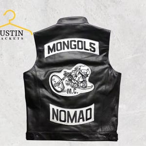 Może przedstawiać: Czarna skórzana kamizelka z białymi naszywkami. Na górnej naszywce widnieje napis "MONGOLS", a na dolnej "NOMAD". Duża naszywka pośrodku przedstawia motocyklistę na motocyklu. Kamizelka wisi na żółtym wieszaku z napisem "JUSTIN JACKETS".