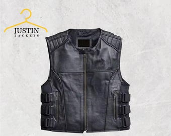 May include: Black leather vest with a zip-up front, multiple pockets, and padded shoulders. The vest has a textured surface and a classic biker style. The brand name "JUSTIN JACKETS" is visible on a yellow hanger.