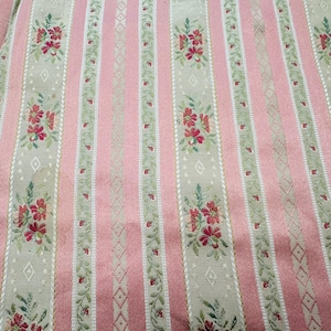 May include: Pink and beige striped fabric with floral and diamond patterns. The fabric features vertical stripes of pink and beige, with floral bouquets and diamond shapes. The floral bouquets are red with green leaves.