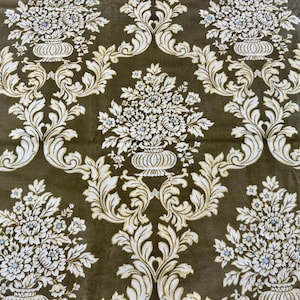 May include: Close-up of a fabric with a repeating floral pattern. The design features white flowers and ornate scrollwork against a dark olive-green background. The floral elements are arranged in a symmetrical, damask-style layout.