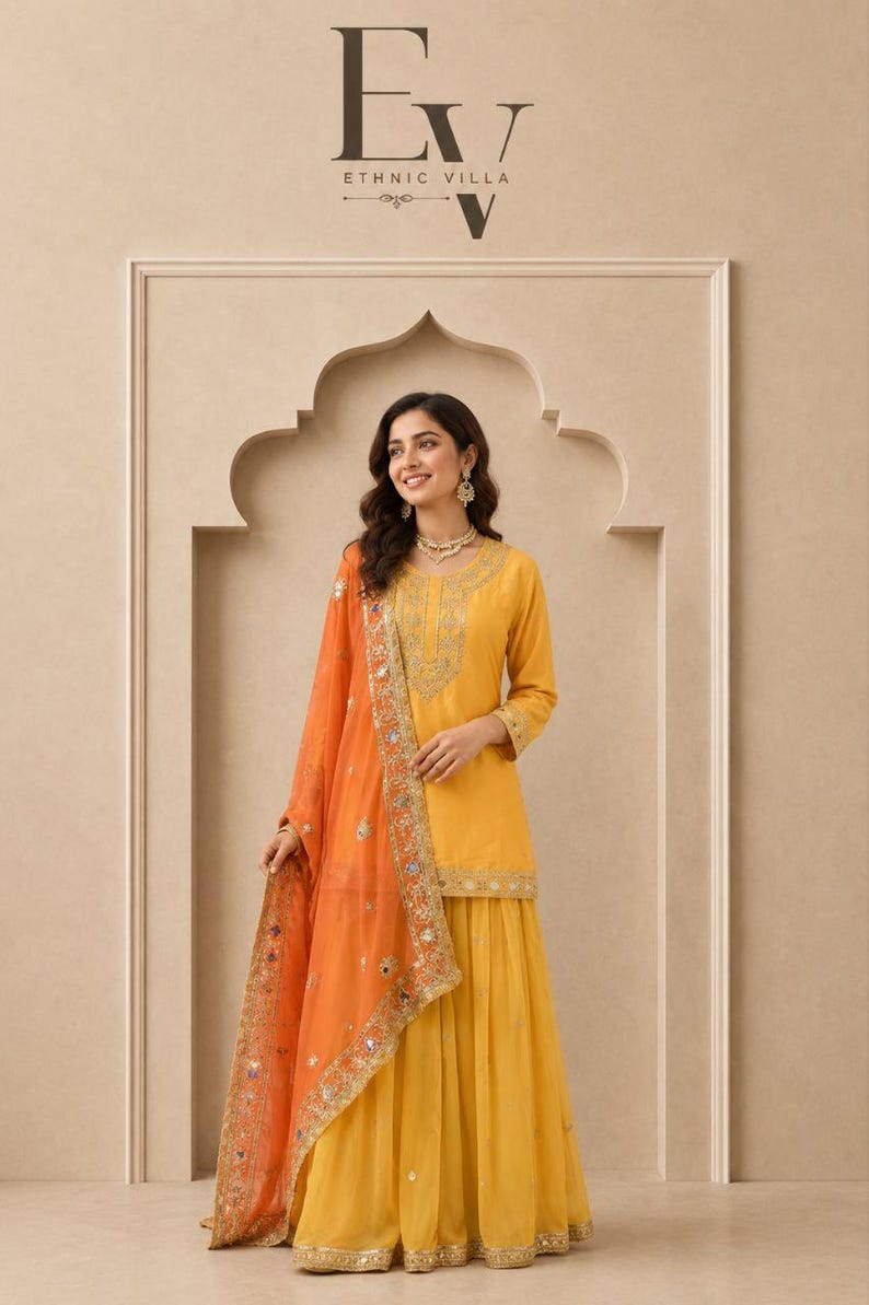 May include: A yellow three-piece outfit consisting of a long-sleeved tunic with gold embroidery, a matching pleated skirt, and an orange sheer dupatta featuring gold borders and small mirror embellishments. The text EV Ethnic Villa is visible.