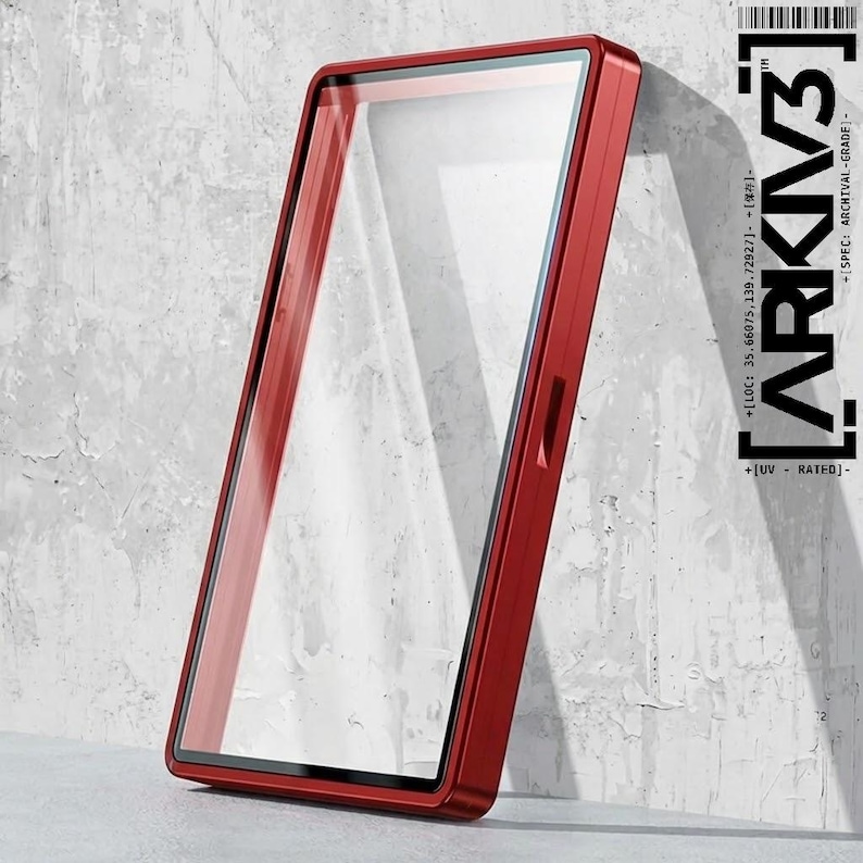 May include: A red rectangular phone case with a clear screen protector. The case has a sleek, modern design and is leaning against a textured gray wall. The text "ARKIV3" is visible on the right side of the case.