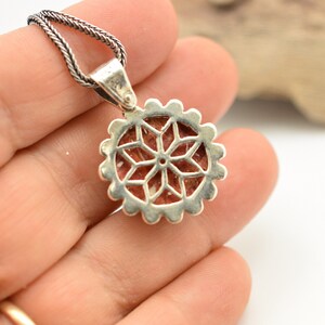 May include: Silver pendant with a red and white stone set in a geometric design. The pendant is attached to a silver chain.