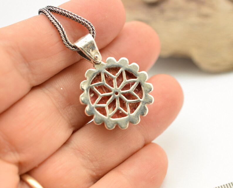 May include: Silver pendant with a red and white stone set in a geometric design. The pendant is attached to a silver chain.