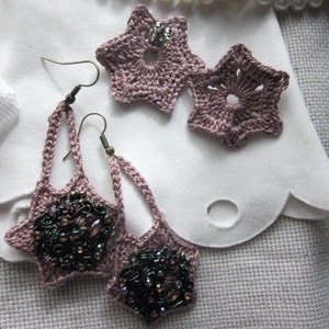 Peut inclure: Une paire de boucles d'oreilles pendantes avec des breloques en forme d'étoile. Les breloques sont en crochet de fil rose et ont un centre perlé. Les boucles d'oreilles sont attachées à des crochets argentés.