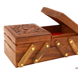 May include: A dark brown wooden jewellery box with a hinged lid and a carved floral design. The box has a red velvet interior. The box is open, revealing the interior.