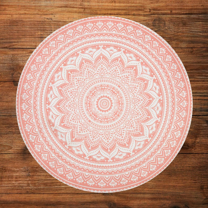Puede incluir: Un dise&ntilde;o de mandala redondo rosa y blanco. El intrincado patr&oacute;n presenta un motivo floral central rodeado de c&iacute;rculos conc&eacute;ntricos de patrones sim&eacute;tricos detallados. El dise&ntilde;o est&aacute; sobre un fondo de madera, creando un contraste de texturas.