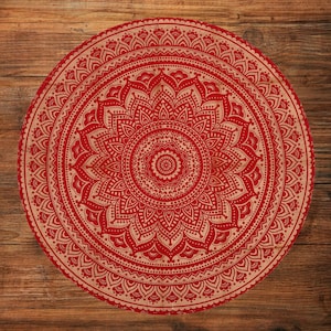 Puede incluir: Un dise&ntilde;o de mandala redondo rojo y beige. El intrincado patr&oacute;n presenta un motivo floral central rodeado de elementos sim&eacute;tricos detallados. El dise&ntilde;o se encuentra sobre un fondo de madera, creando un contraste de texturas y colores.
