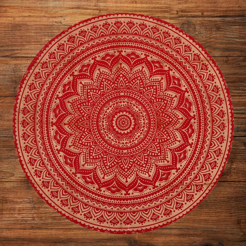 Puede incluir: Un dise&ntilde;o de mandala redondo rojo y beige. El intrincado patr&oacute;n presenta un motivo floral central rodeado de elementos sim&eacute;tricos detallados. El dise&ntilde;o se encuentra sobre un fondo de madera, creando un contraste de texturas y colores.