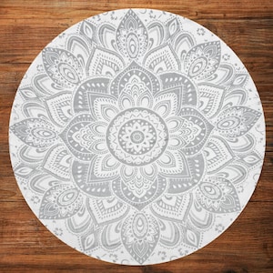 Puede incluir: Un tapiz mandala redondo, blanco y gris, con un intrincado dise&ntilde;o floral. El patr&oacute;n sim&eacute;trico presenta detalles en tonos grises sobre un fondo blanco. El dise&ntilde;o est&aacute; centrado y se irradia hacia afuera.