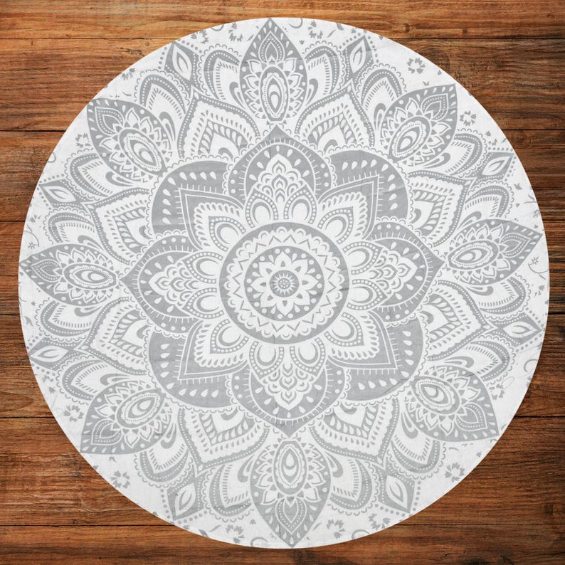 Puede incluir: Un tapiz mandala redondo, blanco y gris, con un intrincado dise&ntilde;o floral. El patr&oacute;n sim&eacute;trico presenta detalles en tonos grises sobre un fondo blanco. El dise&ntilde;o est&aacute; centrado y se irradia hacia afuera.