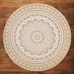 Könnte beinhalten: Runde, beige-weiße Mandala-Tapisserie mit komplizierten floralen und geometrischen Mustern. Die Tapisserie weist ein detailliertes Design auf, das vom Zentrum ausgeht und ein symmetrisches und dekoratives Stück schafft. Auf einer Holzoberfläche platziert.