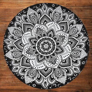 Puede incluir: Un dise&ntilde;o de mandala redondo en blanco y negro. El intrincado patr&oacute;n presenta un motivo floral central rodeado de formas sim&eacute;tricas detalladas. El dise&ntilde;o est&aacute; sobre un fondo negro.