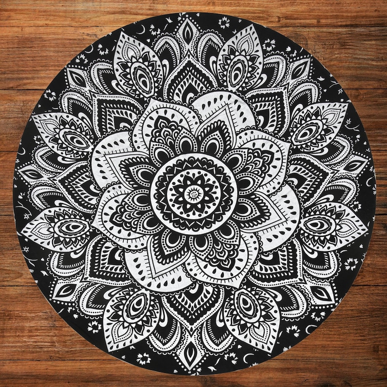 Puede incluir: Un dise&ntilde;o de mandala redondo en blanco y negro. El intrincado patr&oacute;n presenta un motivo floral central rodeado de formas sim&eacute;tricas detalladas. El dise&ntilde;o est&aacute; sobre un fondo negro.