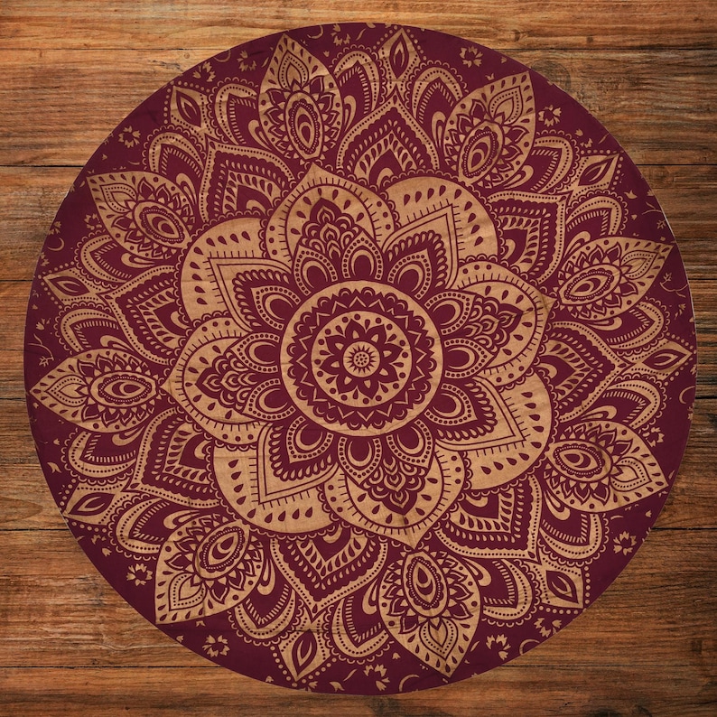 Puede incluir: Un objeto decorativo redondo con un dise&ntilde;o de mandala detallado. El mandala presenta un fondo burdeos con un patr&oacute;n floral dorado. El dise&ntilde;o intrincado es sim&eacute;trico y circular, con un motivo floral central.