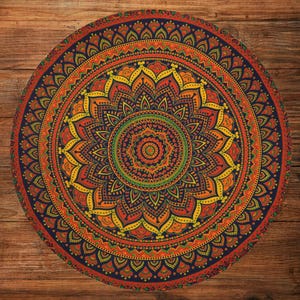 Può includere: Un mandala rotondo con un motivo intricato nei toni dell'arancione, giallo e verde su uno sfondo blu scuro. Il design presenta un motivo floreale centrale circondato da dettagliati motivi geometrici. Il mandala è posto su una superficie di legno.
