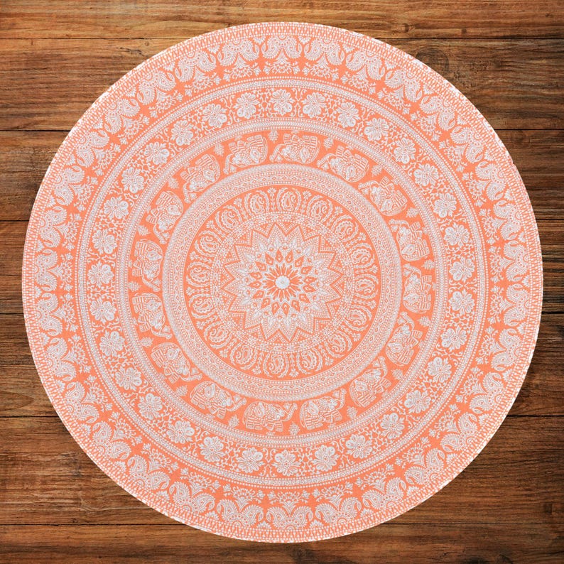 Puede incluir: Tapiz mandala redondo de color coral con intrincados patrones florales y de elefantes blancos. El tapiz es circular, con un dise&ntilde;o central en forma de estrella y elementos de borde detallados. Este textil decorativo es adecuado para diversos usos.