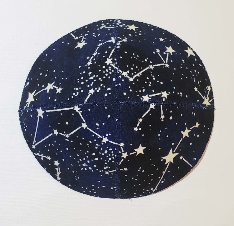 May include: A dark blue kippah with a white constellation pattern. The kippah is made of a soft, textured fabric.