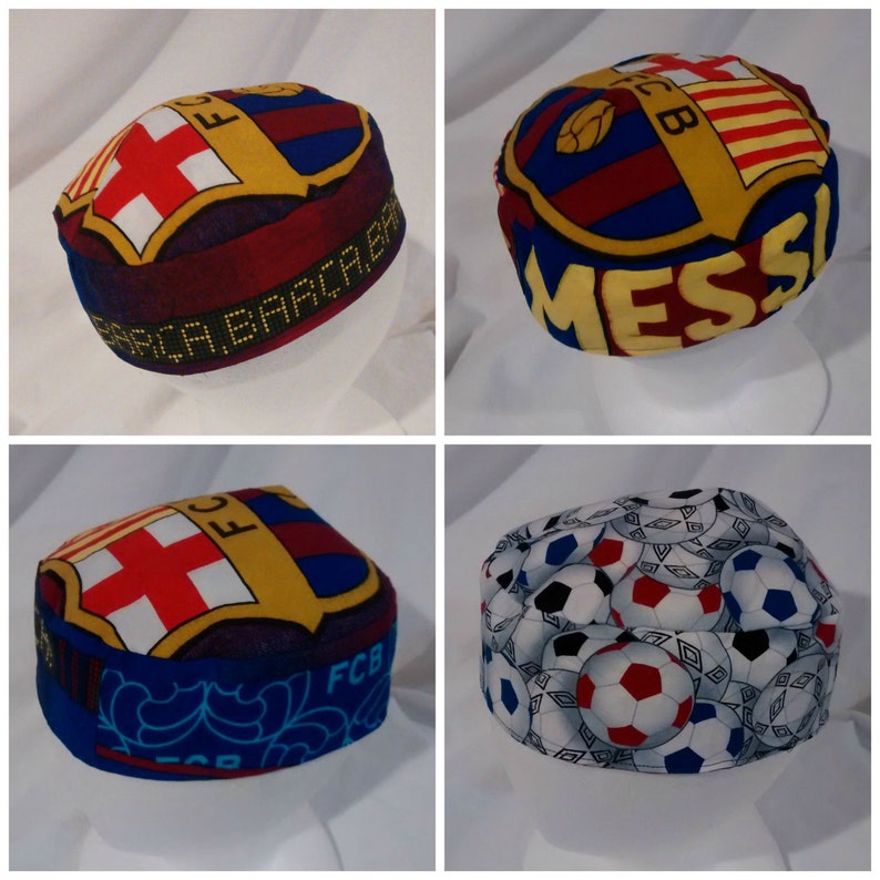 Op de afbeelding: Vier verschillende stoffen mutsen met een voetbalthema. De mutsen zijn allemaal rood, geel en blauw met een voetbalontwerp. Een muts heeft het FC Barcelona logo en het woord "Messi" erop. Een andere muts heeft een voetbalontwerp met de woorden "FCB" erop.