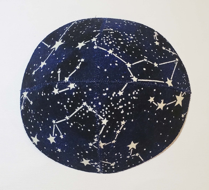 May include: A dark blue kippah with a white constellation pattern. The kippah is round and has a white seam around the edge.