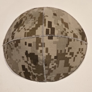 May include: A brown and tan camouflage patterned kippah, a traditional Jewish head covering.