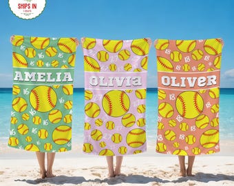 May include: Three personalized softball beach towels. Each towel features a name, softball graphics, and numbers. The towels are in shades of green, pink, and coral, with a blue sky and ocean background.