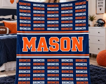May include: A navy blue fleece blanket featuring a repeating pattern of the word BRONCOS in white and orange text. A large orange horizontal stripe across the center displays the name MASON in bold white capital letters.