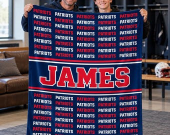 May include: A navy blue fleece blanket featuring a repeating pattern of the word Patriots in white and red text. A central horizontal band displays the name JAMES in large red block letters with a white outline against a navy background.