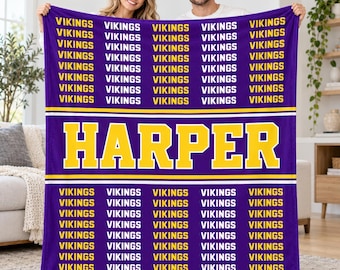 May include: A purple fleece blanket featuring a repeating pattern of the word VIKINGS in yellow text. A central horizontal yellow band displays the name HARPER in large yellow block letters, bordered by thin white stripes above and below.
