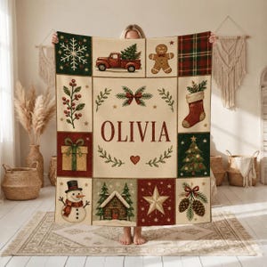 May include: A rectangular throw blanket featuring a grid of Christmas-themed illustrations including a red truck, gingerbread man, stocking, snowman, cabin, and star. The center panel displays the name OLIVIA in large red letters.