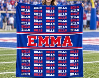 May include: A rectangular blue fleece blanket featuring a repeating pattern of the word BILLS in white and red text. A central horizontal band displays the name EMMA in large red letters with a white outline, set against a solid blue background.