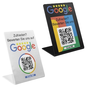 May include: Two Google review stands, one black and one white. Each stand features the Google logo, a QR code, and the text "Zufrieden? Bewerten Sie uns auf Google" and "SCAN ME". They are designed for counter or table display.