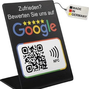 Könnte beinhalten: Ein schwarzer Displayständer mit dem Google-Logo in Rot, Gelb, Blau und Grün sowie einem QR-Code. Der Text lautet "Zufrieden? Bewerten Sie uns auf Google" und "Made in Germany" auf einem Anhänger.