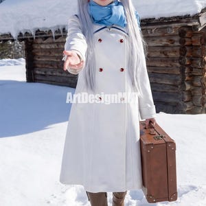 May include: A white double-breasted coat with red buttons and a blue scarf. The coat is knee-length and worn in a snowy outdoor setting. A brown suitcase is held in one hand. The text "ArtDesignHK" is visible on the coat.