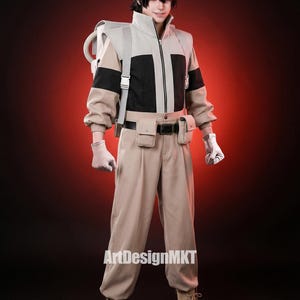 Könnte beinhalten: Ein beiges und schwarzes Cosplay-Outfit mit passender Kappe und Stiefeln. Das Outfit umfasst eine Jacke, eine Hose und einen Werkzeuggürtel. Auf dem Rücken wird ein Rucksack getragen. Das Outfit ist mit Handschuhen ausgestattet. Der Text "ArtDesignMKT" ist sichtbar.