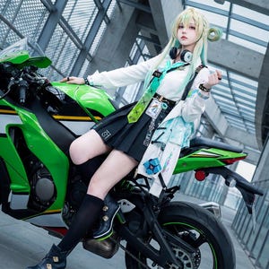 Può includere: Una moto sportiva verde e nera con dettagli bianchi. La moto è parcheggiata di fronte a un edificio moderno. Le ruote della moto sono nere e il sedile è nero. Il design è elegante e moderno.
