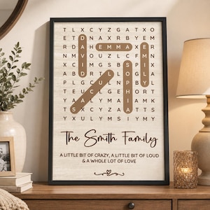 May include: A framed word search print featuring a grid of letters with highlighted names David, Emma, Sophia, and Emily. Below the grid, the text reads The Smith Family, followed by A LITTLE BIT OF CRAZY, A LITTLE BIT OF LOUD & A WHOLE LOT OF LOVE.