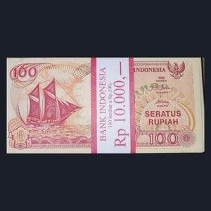 Könnte beinhalten: Ein Stapel indonesischer 100 Rupiah-Banknoten, gebunden mit einem rot-weißen Papierband. Die Banknoten zeigen eine Segelschiff-Illustration und den Text "BANK INDONESIA" und "SERATUS RUPIAH".