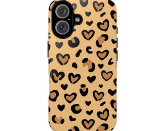 May include: A phone case with a tan background and a pattern of black and brown hearts and leopard spots. The case has a camera cutout and black side buttons.