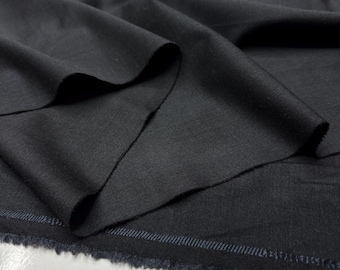 May include: A close-up of a dark grey fabric with folds and a raw edge. The material is a medium-weight woven textile, possibly wool or a wool blend, with a subtle sheen. The fabric is draped, showing its texture and how it hangs.