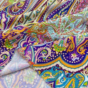 May include: Close-up of paisley fabric with a vibrant pattern. The fabric features a mix of colours, including purple, blue, green, orange, and yellow. The design is intricate, with swirling shapes and floral elements. The fabric is folded, showing the texture and detail.